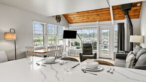 A dining area with a table set for two, a television, and a view of a marina. - Embarcadero Resort Hotel & Marina (Newport)