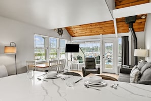 A dining area with a table set for two, a television, and a view of a marina. - Embarcadero Resort Hotel & Marina (Newport)
