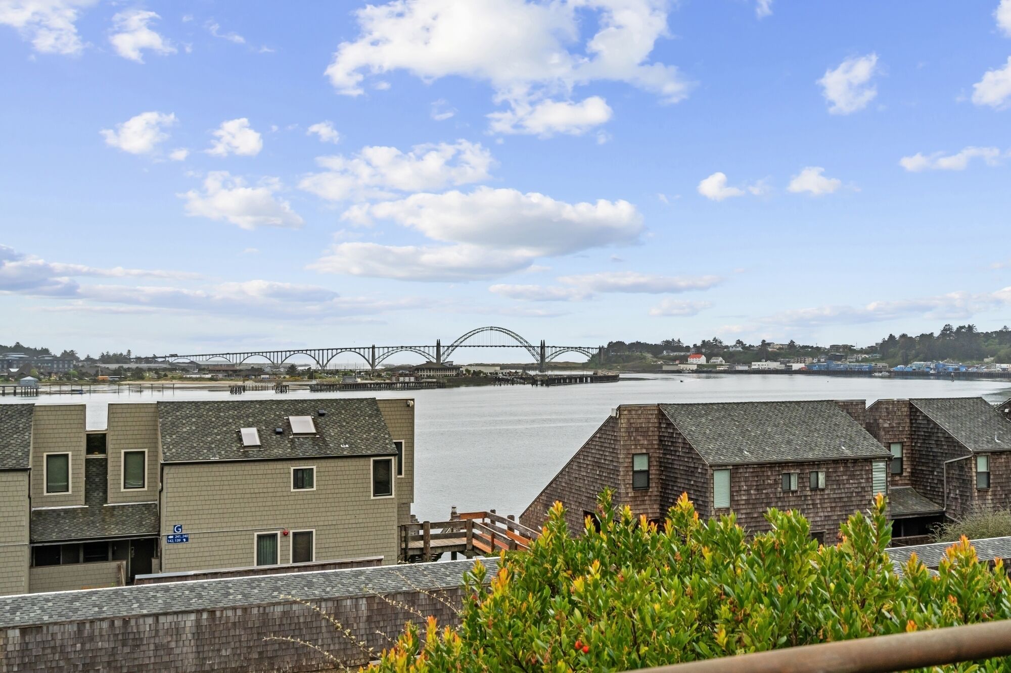 A view of a bridge over water, buildings with sloped roofs, and a clear sky.