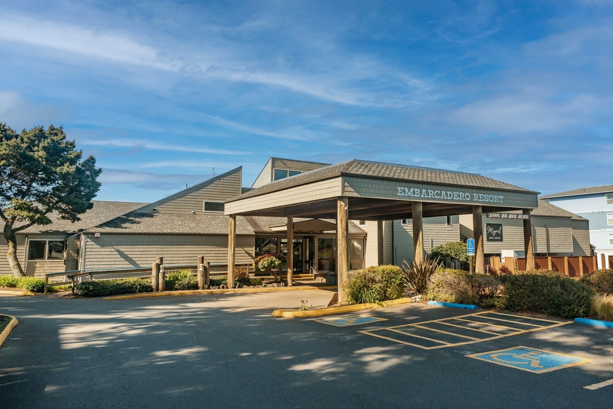 A building with a covered entrance labeled 'EMBARCADERO RESORT' and a parking lot with marked handicapped spaces.