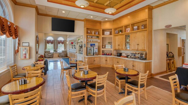 A hotel lobby with wooden furniture, a bar area, and a television mounted on the wall.