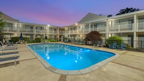 A hotel with a swimming pool, multiple balconies, and a well-lit exterior.