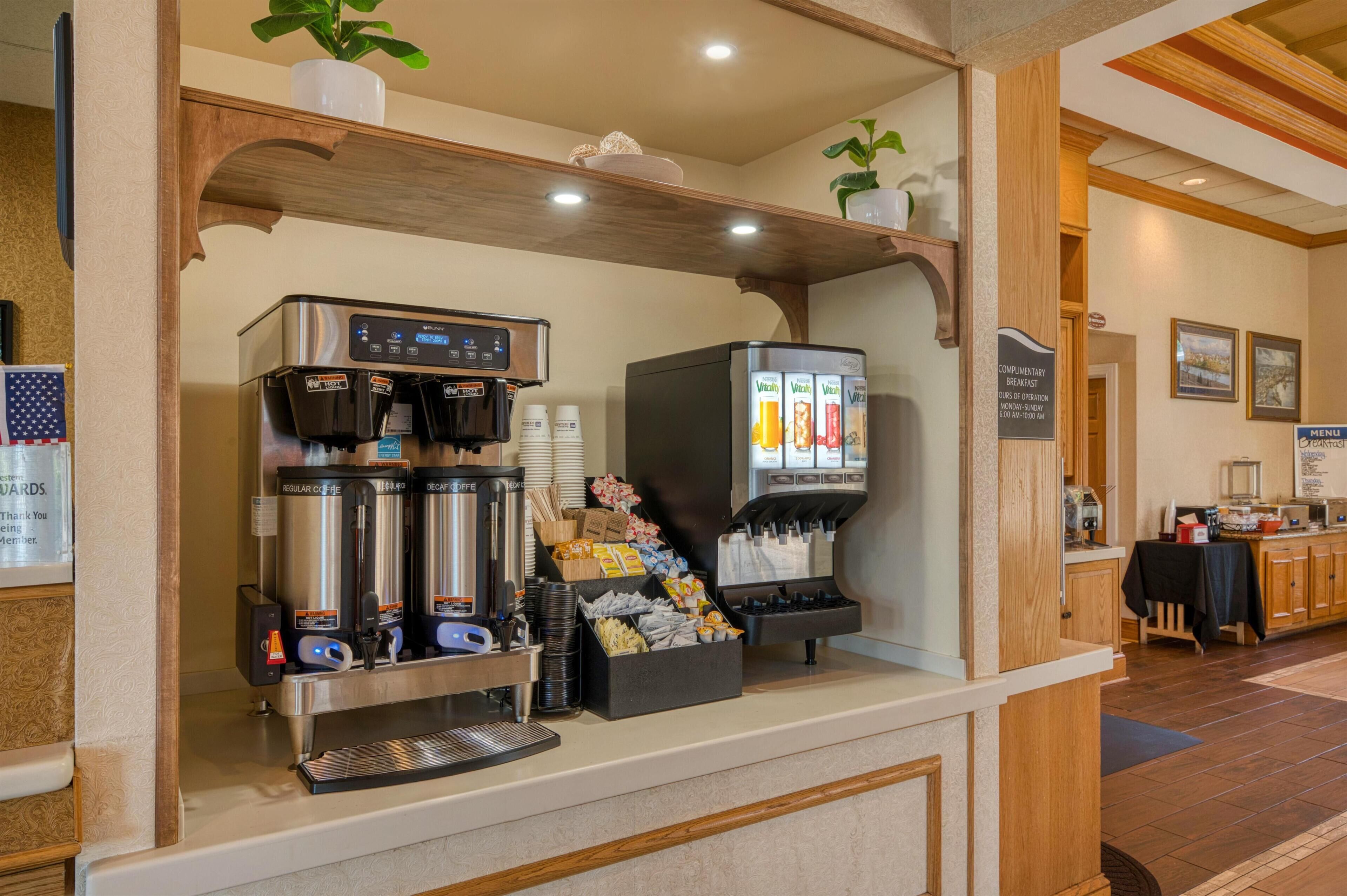 Una estación de café con varias máquinas de café, un dispensador de bebidas y una barra de aperitivos.