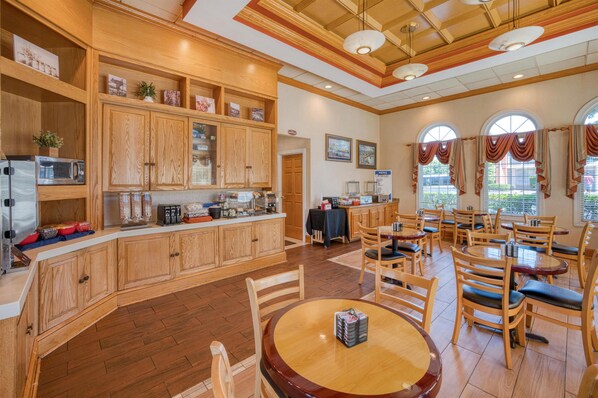 A restaurant with wooden cabinets, a counter, and dining tables.