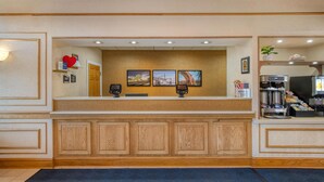 A reception desk with a wooden panel design, a coffee machine, and framed pictures on the wall.