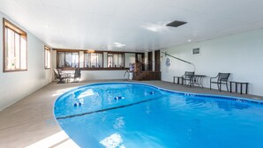 An indoor swimming pool with clear lanes, a sunlit room with a view, and a staircase leading to an upper level.