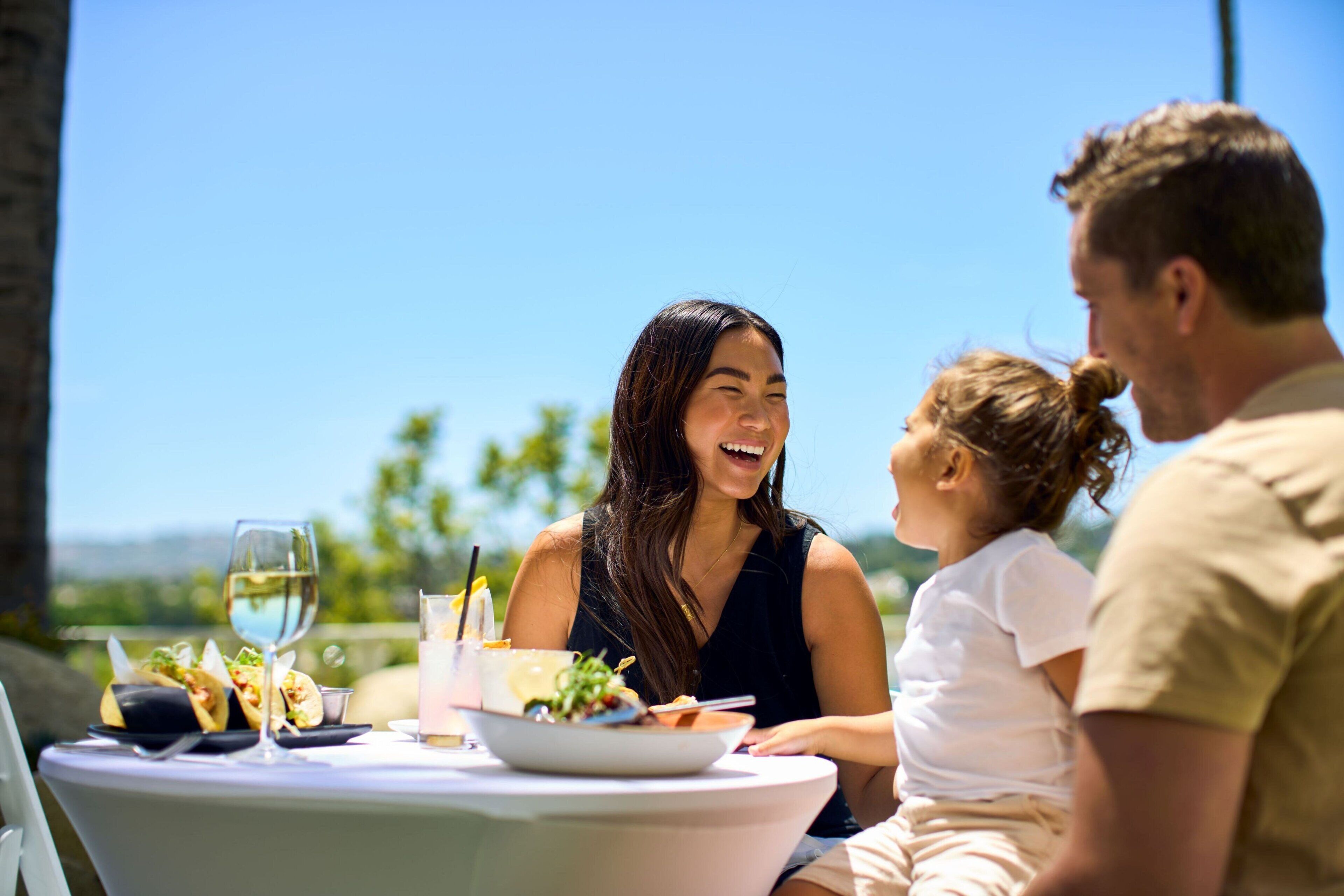 Una mesa con comida y bebidas, cielo despejado y vistas a la vegetación al fondo.