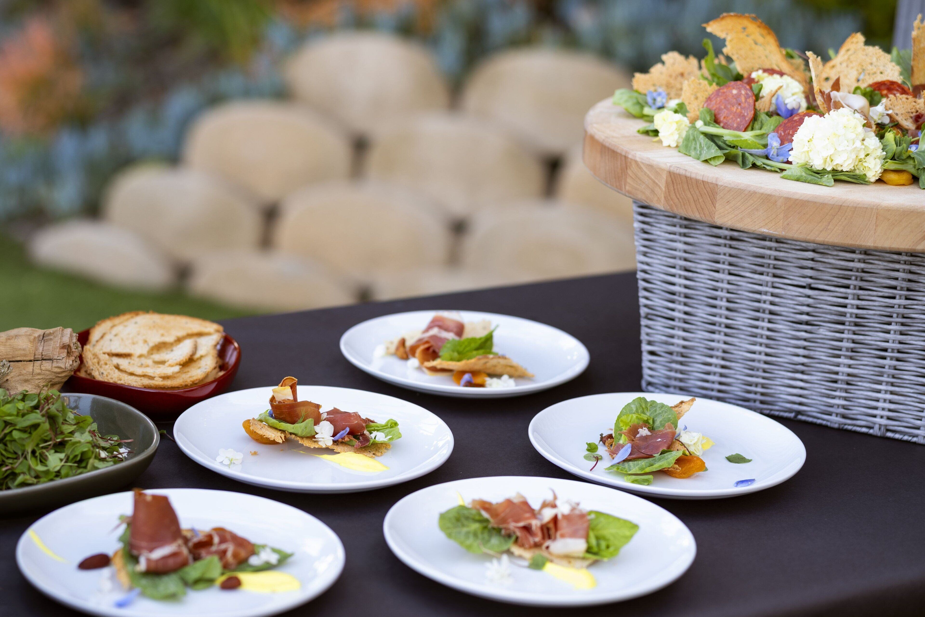 A table with plates of food, a basket of bread, and a bowl of salad.