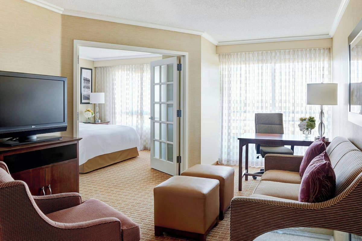 A hotel room with a bed, a television, a desk with a chair, and a sofa.