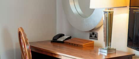 Un bureau en bois avec un téléphone, une lampe et une petite boîte.