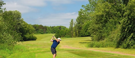 A golf course with a clear path, surrounded by lush greenery and trees.