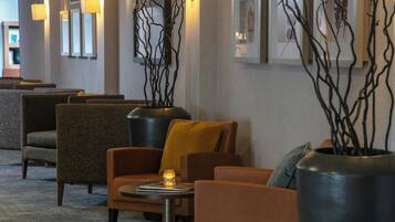 A lobby with seating areas, a coffee table, and decorative branches in vases.