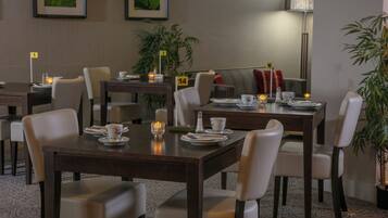 A dining area with tables set for four, chairs, and a lamp.
