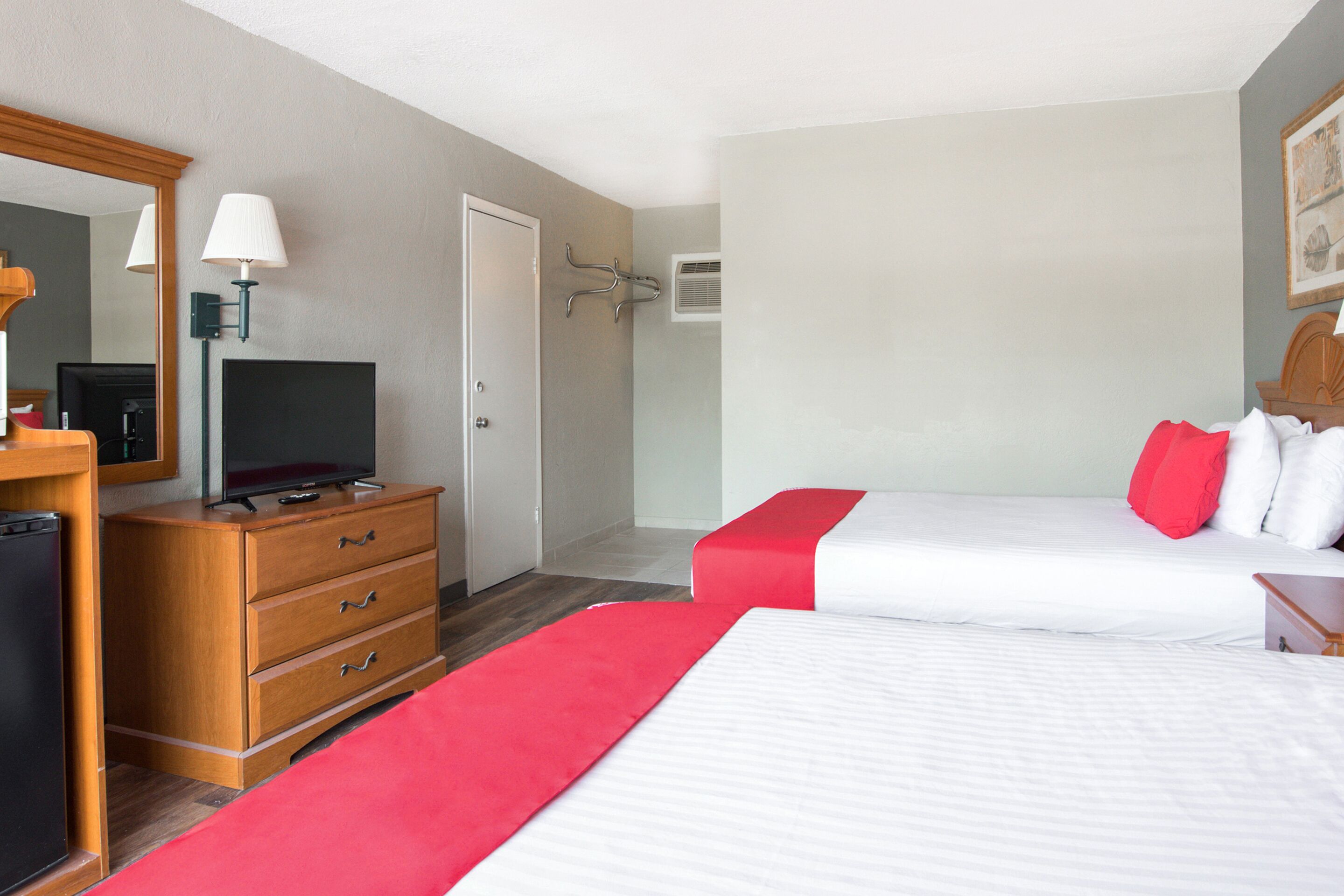 Une chambre d’hôtel avec deux lits, une télévision, une commode et un miroir.