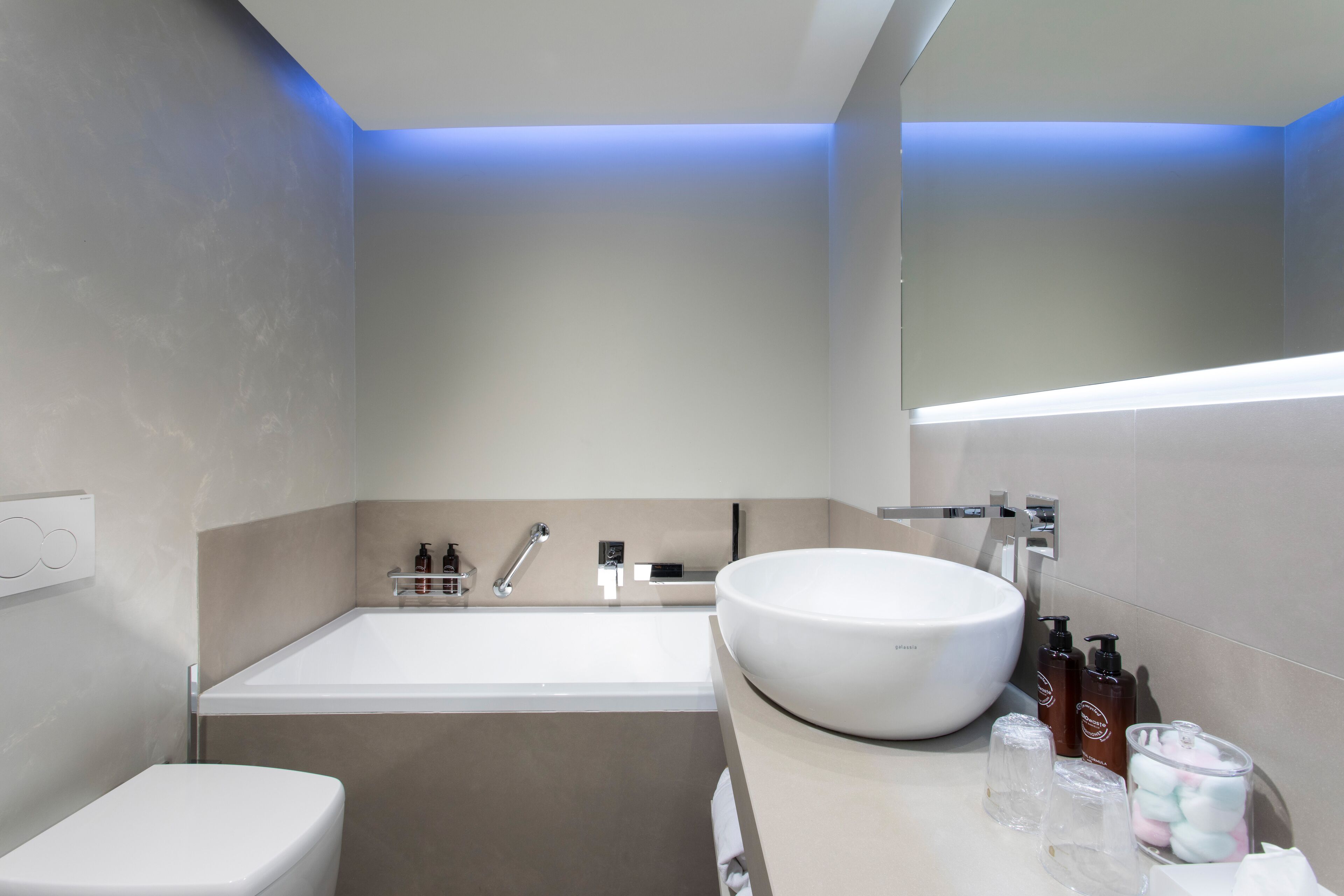 A modern bathroom with a bathtub, toilet, and large sink.