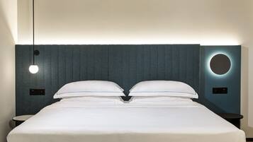 A neatly made bed with a headboard featuring a circular light fixture and a textured wall.
