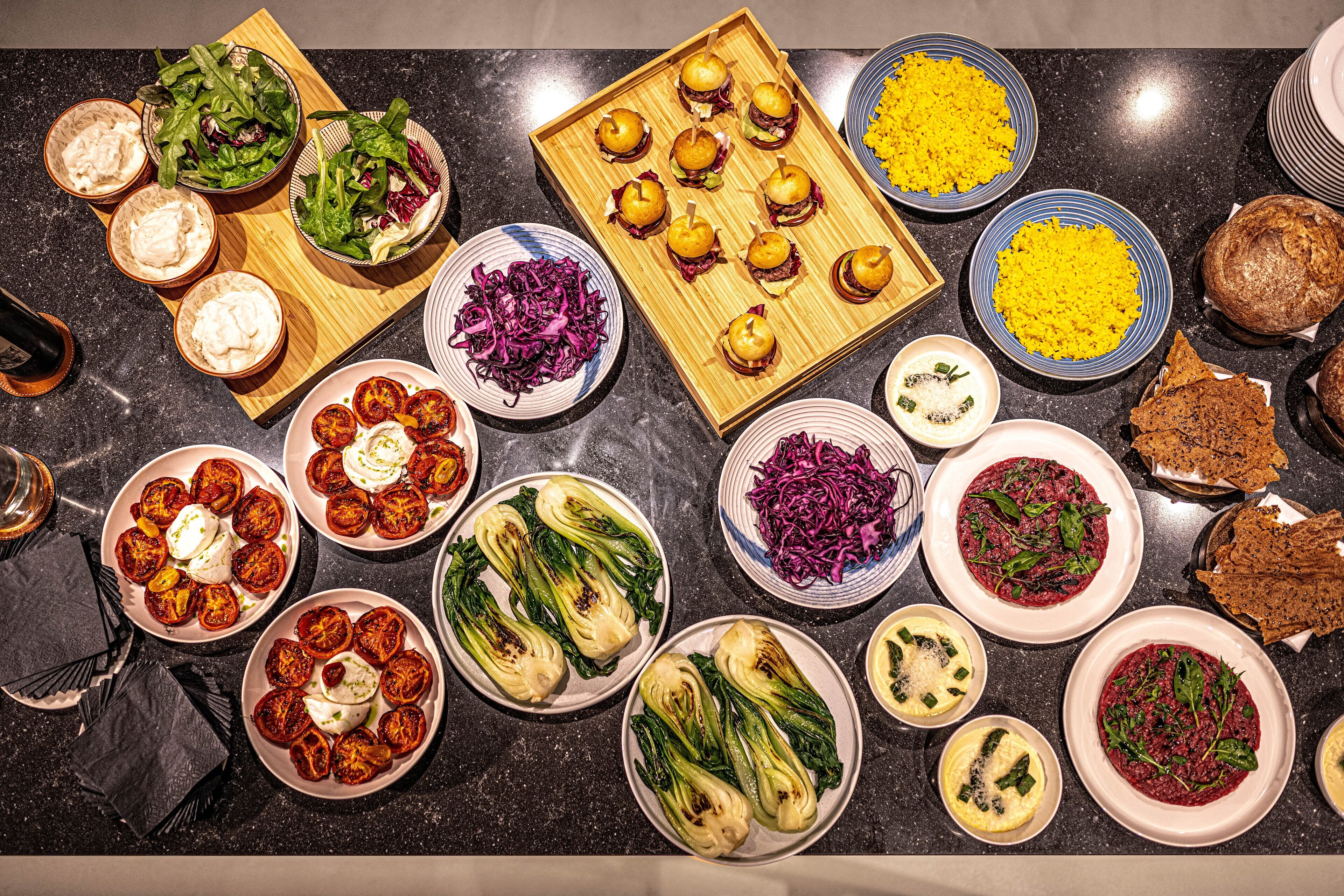 Variedad de platos que incluyen ensaladas, verduras a la parrilla y pan.