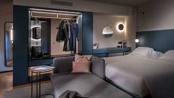 Una habitación de hotel moderna con una cama grande, un área de descanso, un tocador con espejo y un perchero.