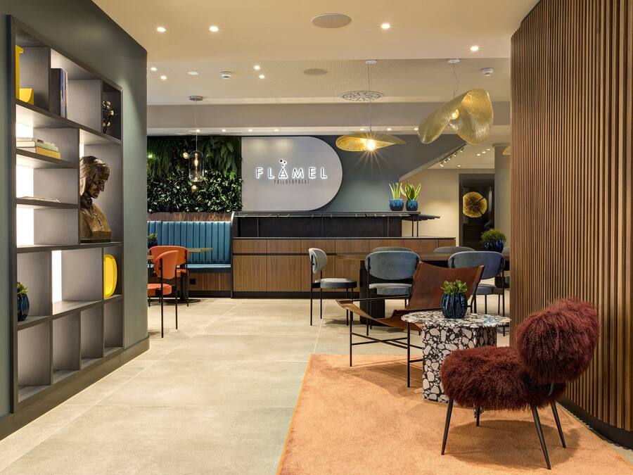 Un intérieur moderne comprenant un comptoir d’accueil, un espace détente et une bibliothèque.