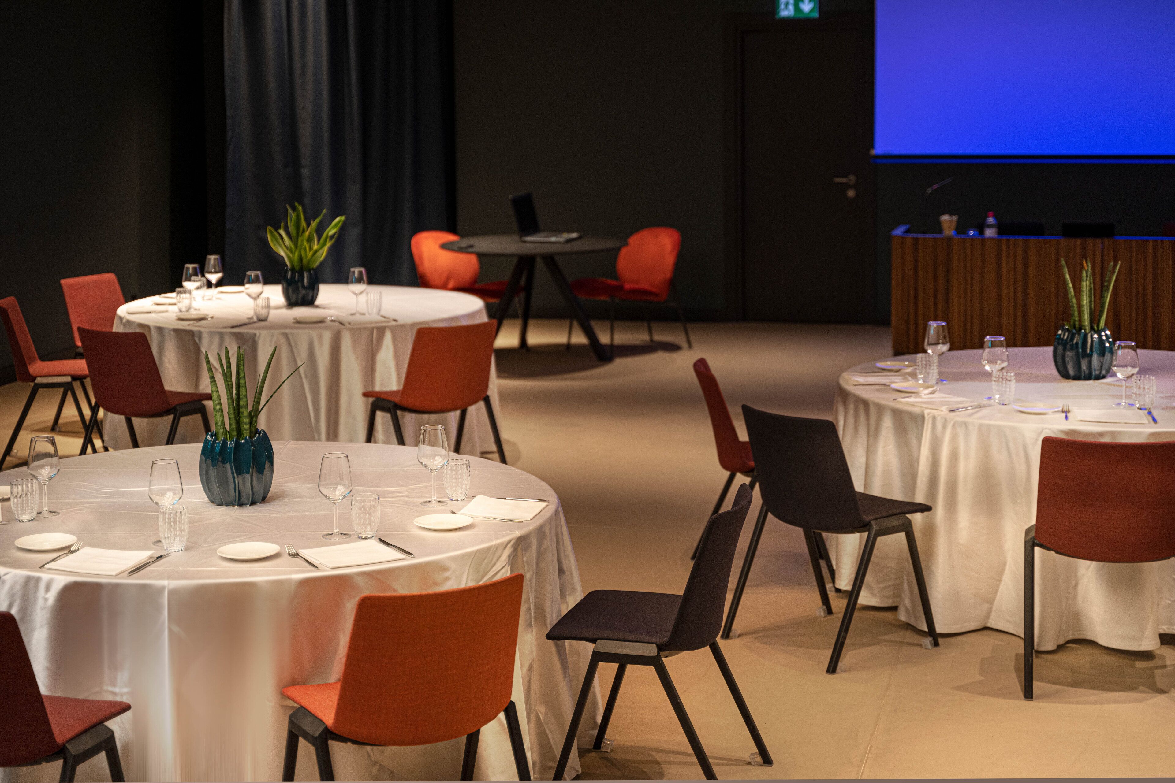 A conference room with round tables, chairs, and a projection screen.