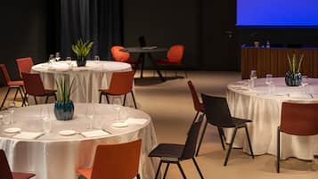 A conference room with round tables, chairs, and a projection screen.