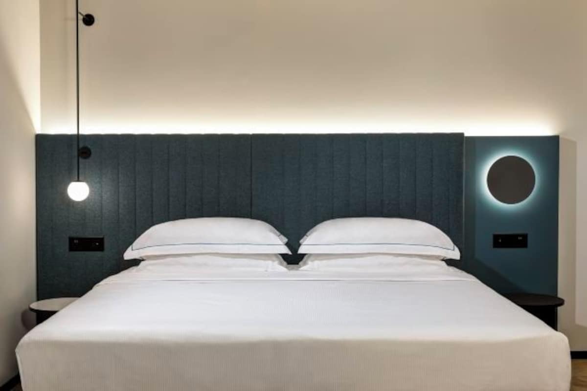 Una habitación de hotel moderna con una cama grande, una lámpara redonda de pared y una luz circular en la pared.