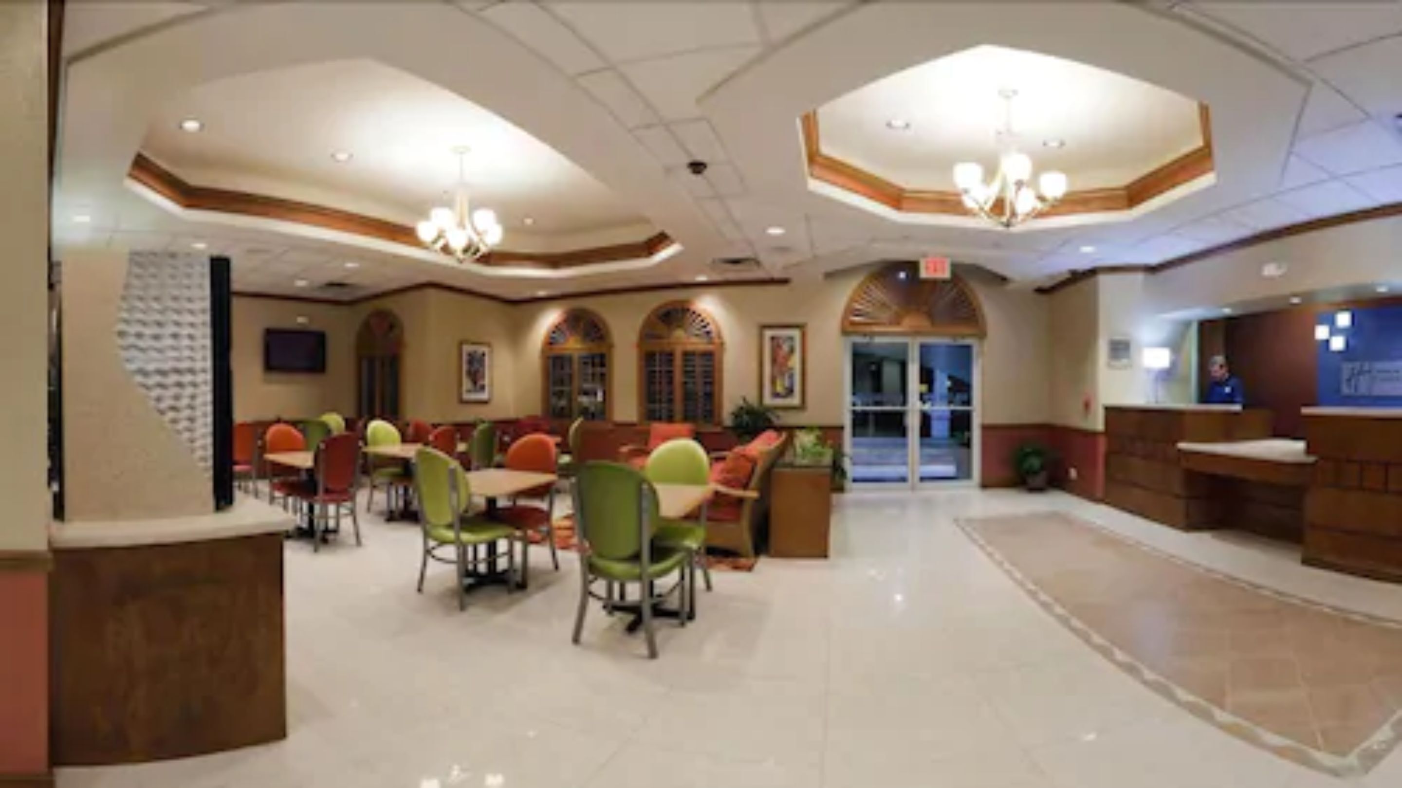 A spacious lobby with a central seating area, a reception desk, and a large arched doorway leading to another section.