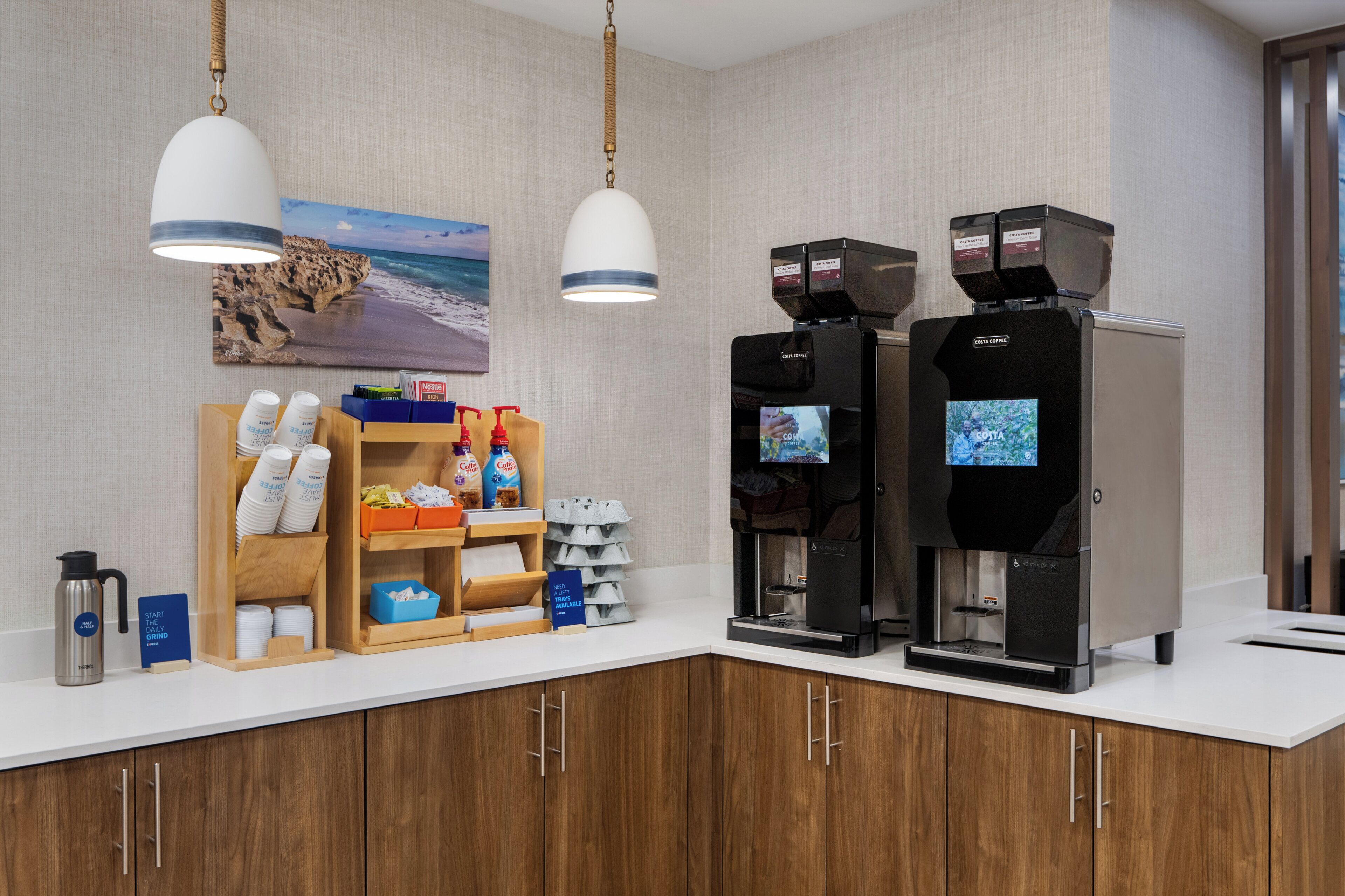 A coffee station with two coffee machines, a coffee grinder, and a sign indicating the start of the grind.