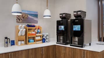 Un espace dédié au café, équipé de deux machines à café, d’un moulin à café et d’un panneau indiquant le début du processus de mouture.