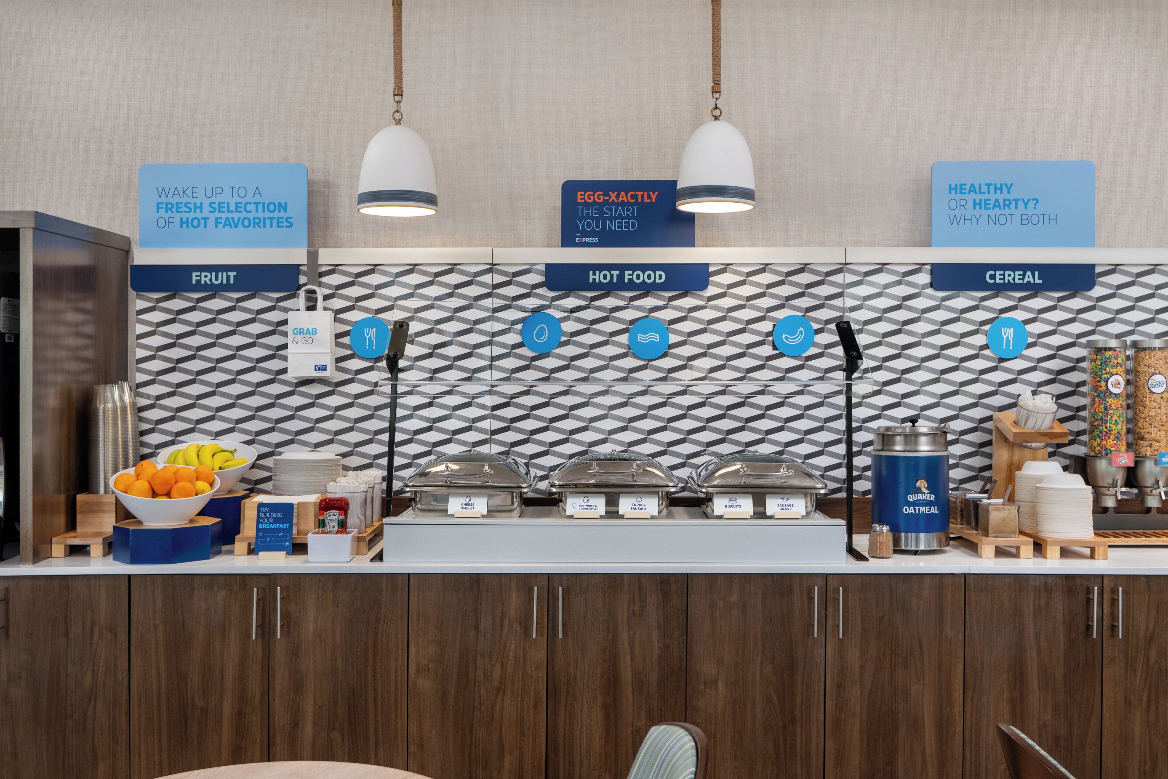 A breakfast buffet area with labeled sections for fruit, hot food, and cereal.