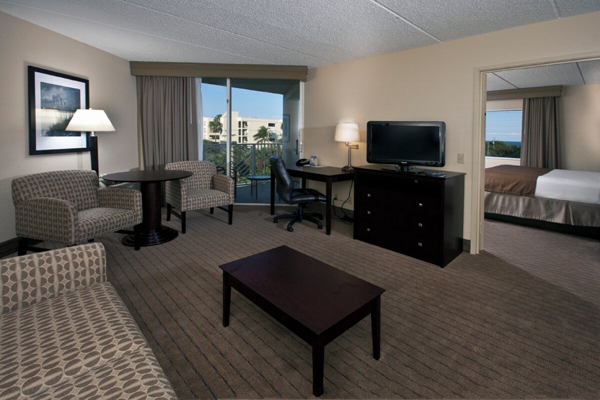Une chambre d’hôtel avec un canapé, une petite table, une télévision, un bureau et un lit.