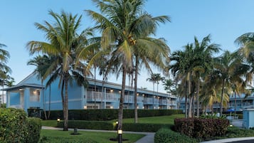 A resort with a blue building, palm trees, and a well-maintained garden.