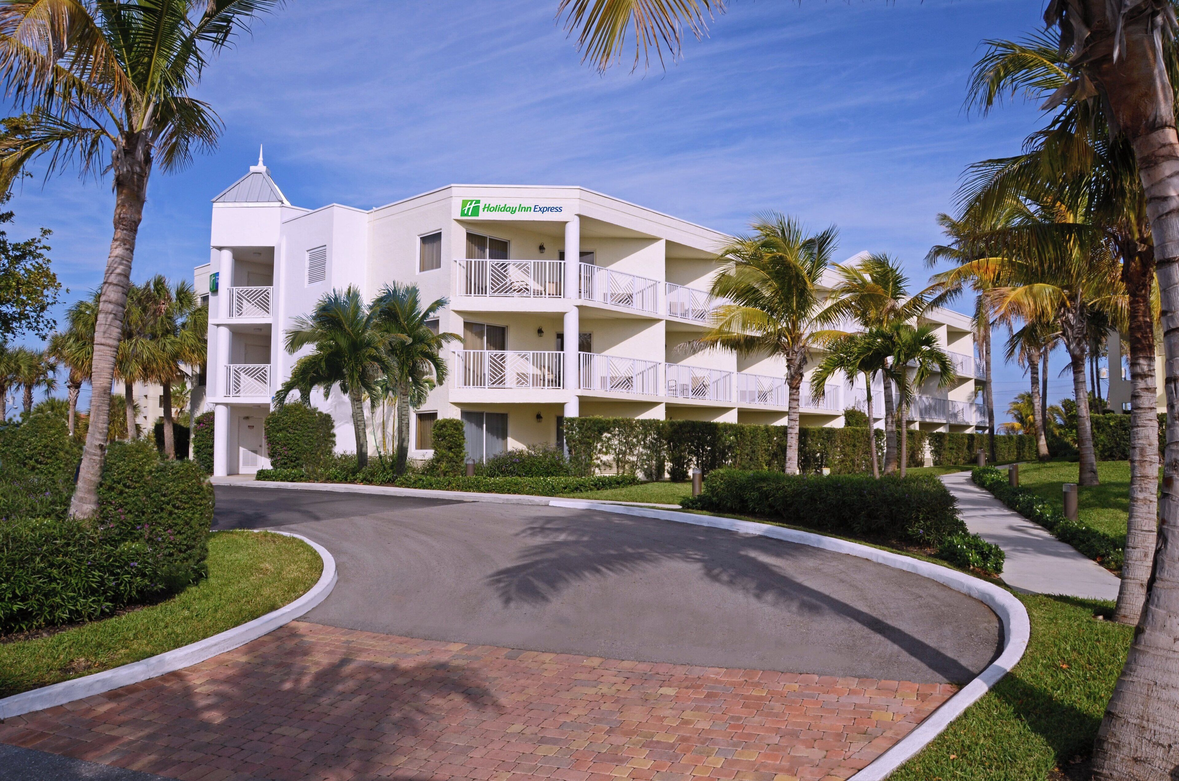 Ein Holiday Inn Express Hotel mit weißer Fassade, mehreren Balkonen und Palmen.