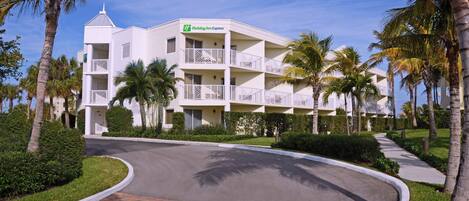Un hotel Holiday Inn Express con facciata bianca, diversi balconi e palme.