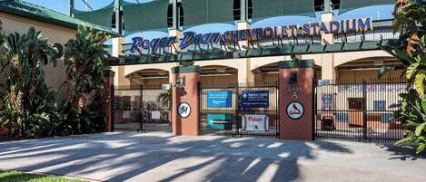 The entrance to the Roger Dean Chevrolet Stadium with a gated entrance, palm trees, and a clear sky.