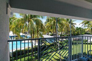 Zona de piscina con palmeras y vista a un edificio.