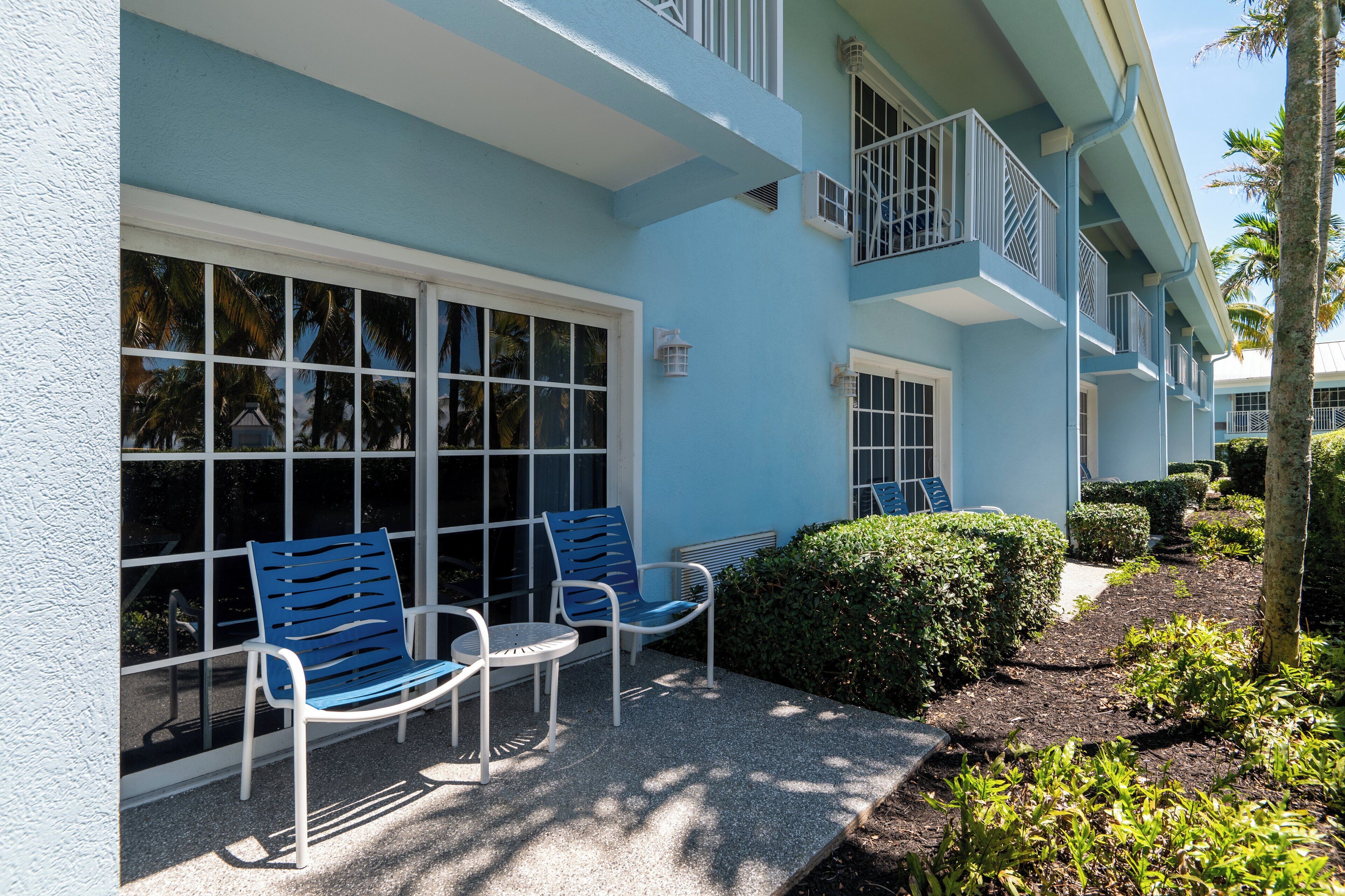 A building with a blue exterior, large windows, and a balcony with white railings.
