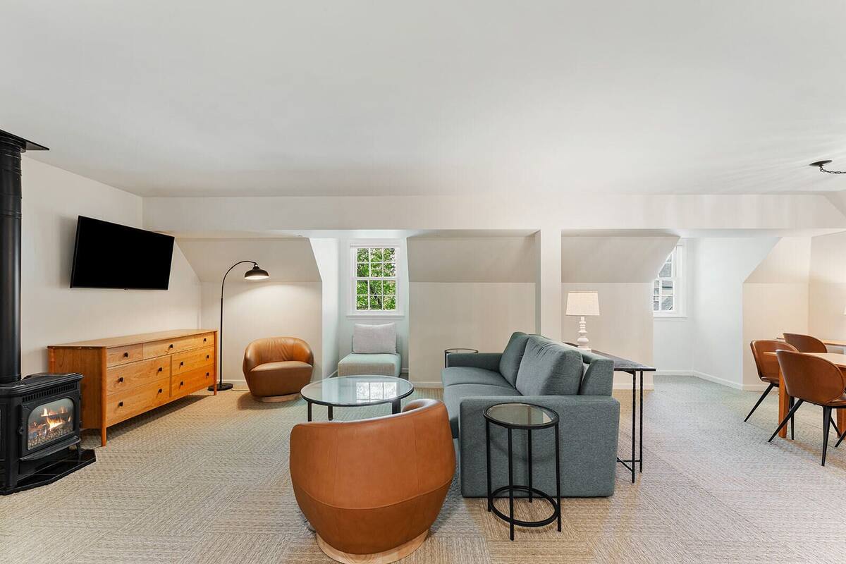 A modern living room with a fireplace, sofa, chairs, and a dining area.