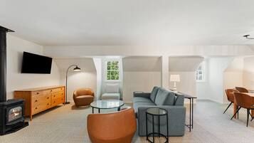 A modern living room with a fireplace, sofa, chairs, and a dining area.