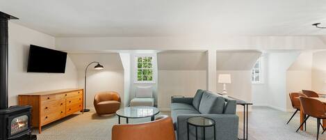 A modern living room with a fireplace, sofa, chairs, and a dining area.