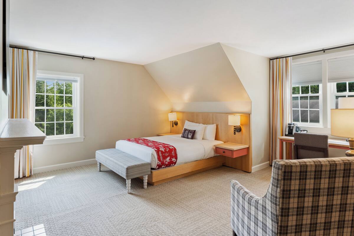 A bedroom with a bed, bedside lamps, a desk, and a chair.