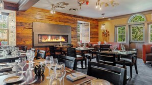 Un restaurante con paredes de madera, chimenea y varias mesas dispuestas para comensales.