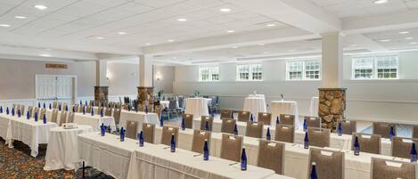 A conference room with rows of tables, chairs, and blue water bottles.