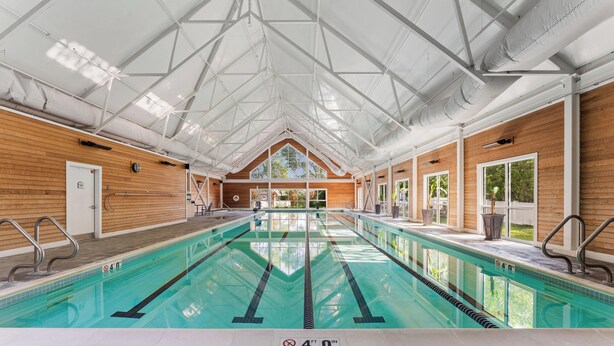 Una amplia piscina cubierta con techo alto y paredes de madera.