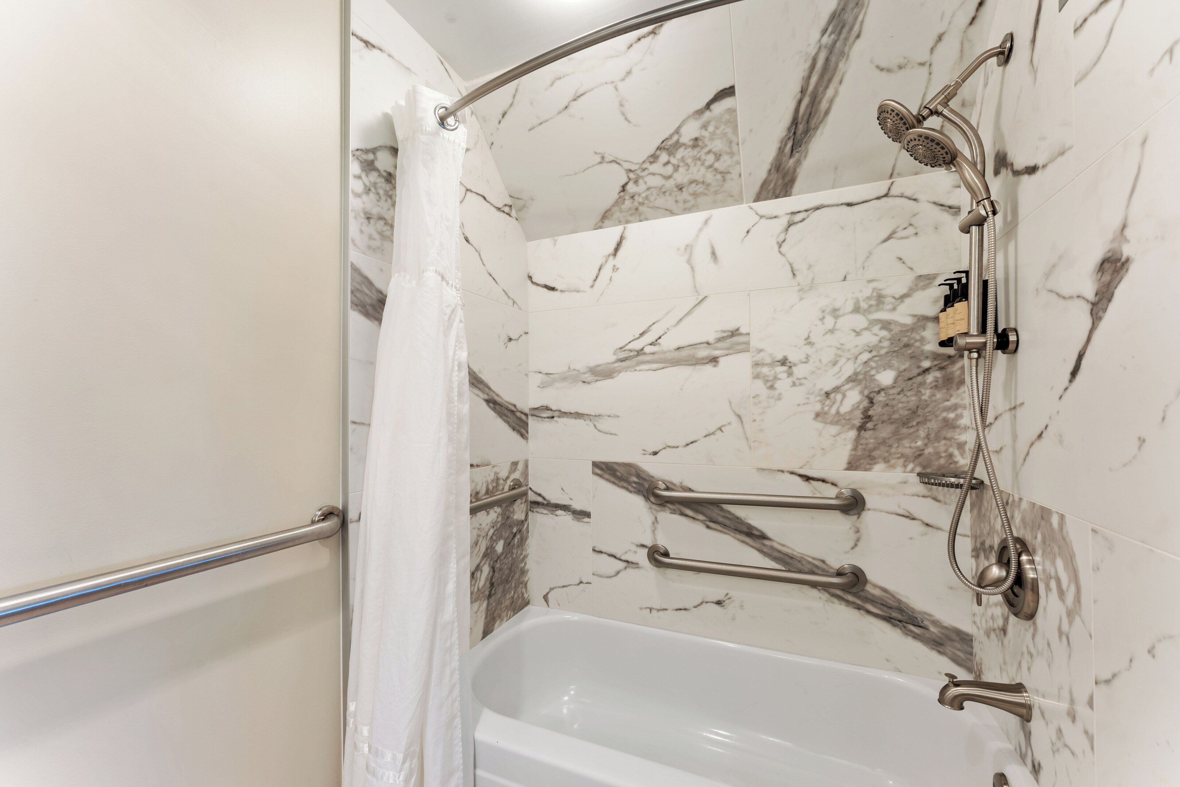 Ein Badezimmer mit Dusche, Badewanne und Marmorwänden.