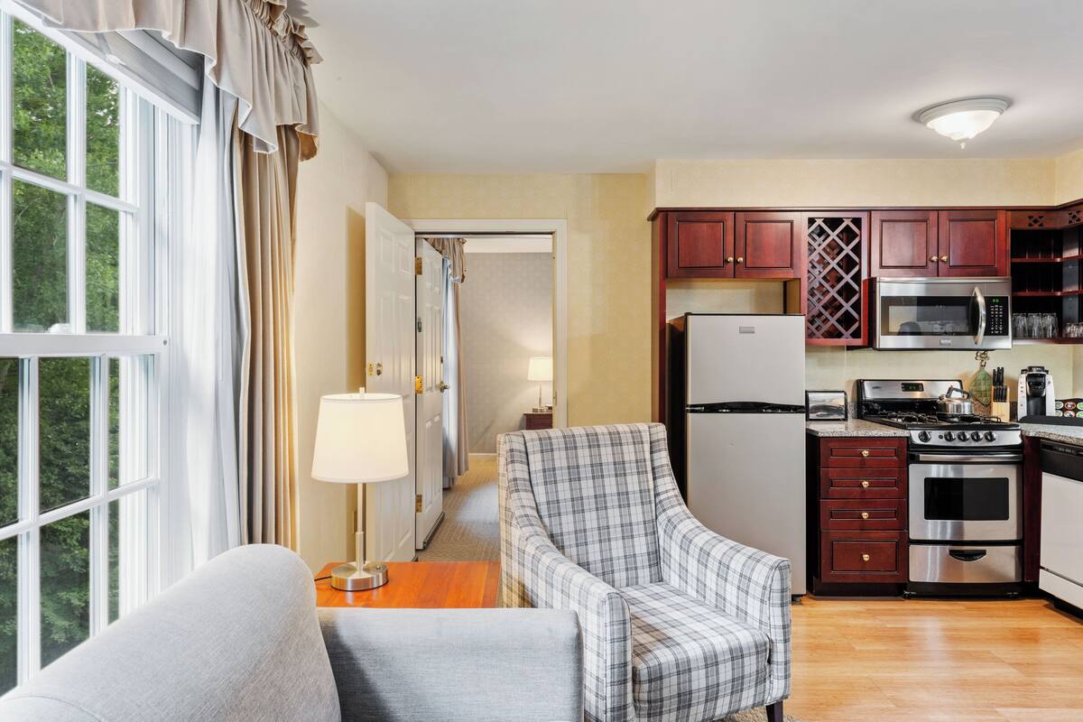 A compact kitchen with modern appliances, a dining area with a sofa, and a view through a window.