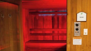 A sauna room with wooden walls and a red light. There is a sign indicating the room is a sauna.