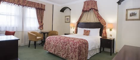 Quarto de hotel com uma cama grande, duas mesas de cabeceira, uma escrivaninha e uma cadeira.