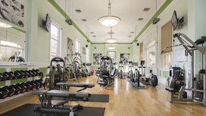 Une salle de sport équipée de divers appareils d’exercice, notamment des tapis de course, des haltères et des appareils de musculation.