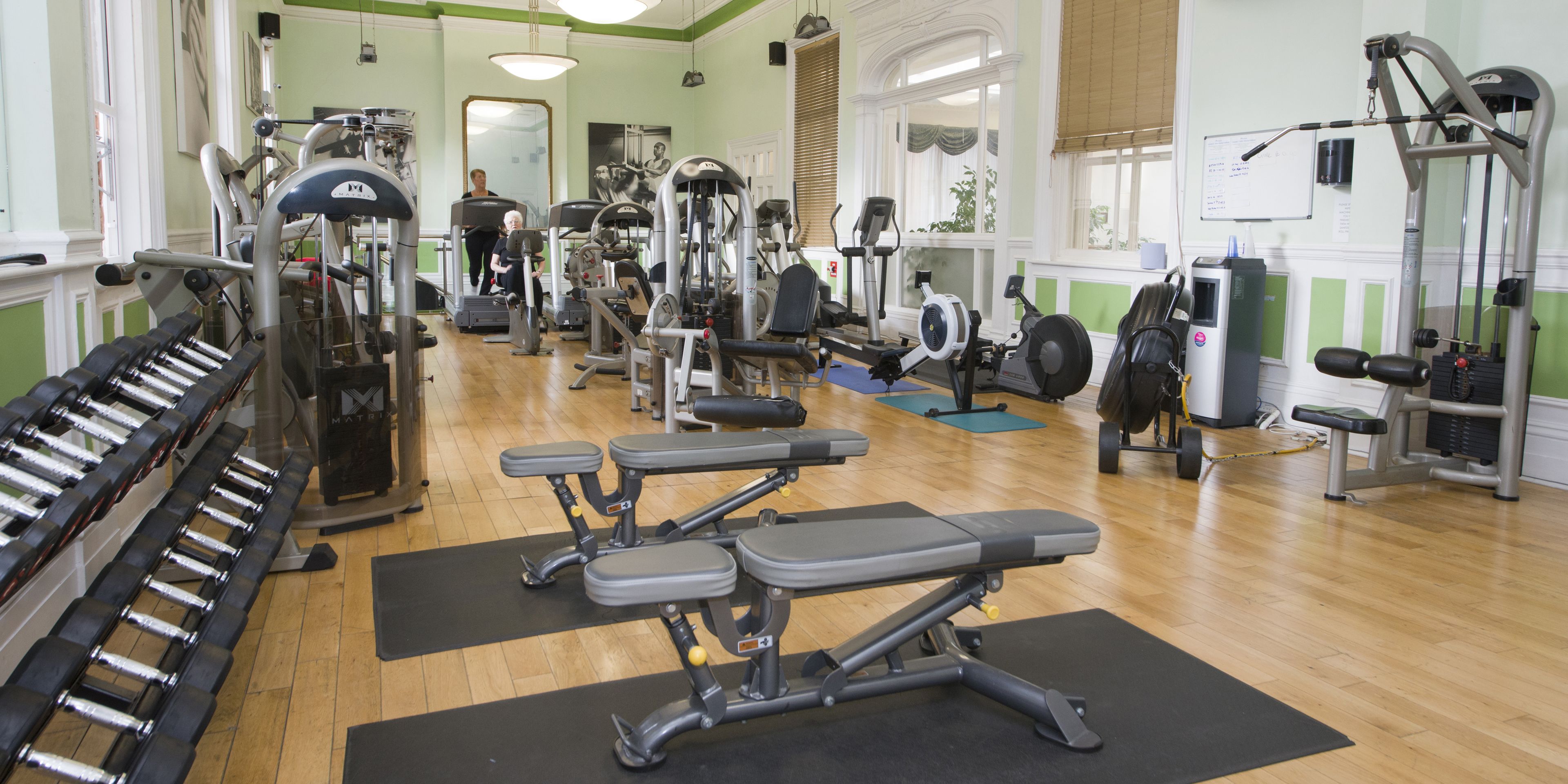 A gym with various exercise equipment, including treadmills, weight machines, and free weights.